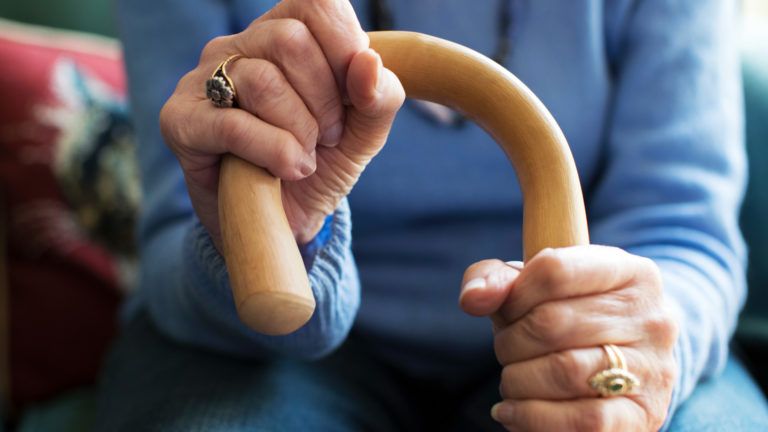 Elderly Woman's hands hold her walking stick