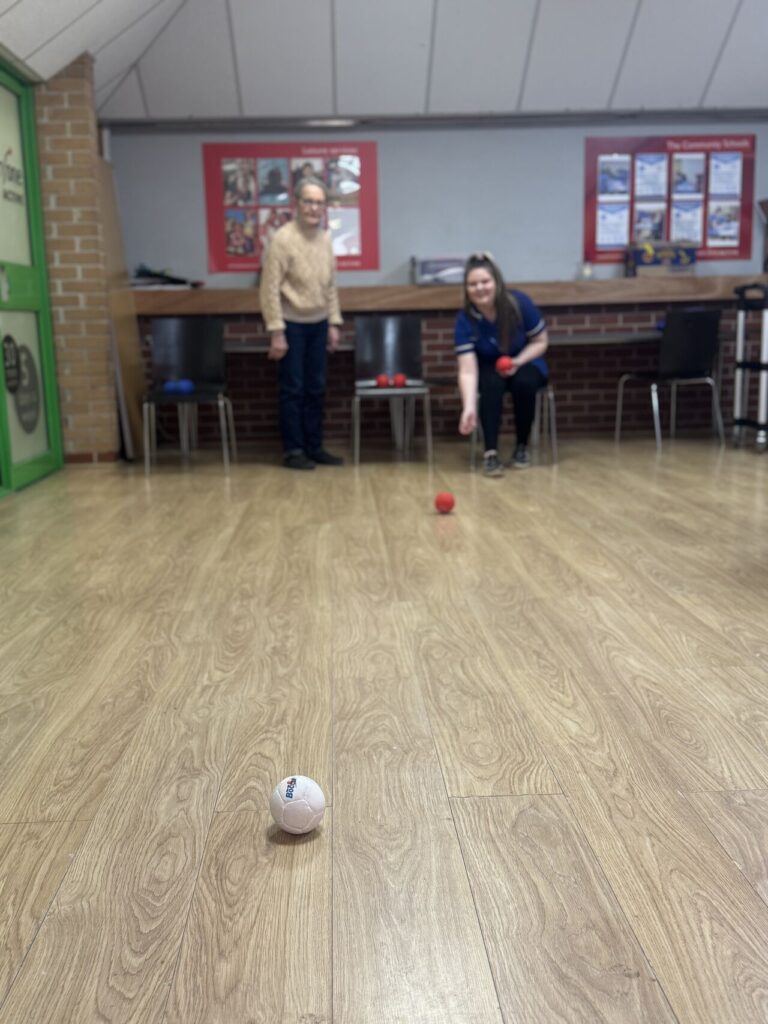Christies carer playing indoor bowls with respite care client at the Mid Suffolk Leisure Centre as part of our supporting family caregivers initiative in Stowmarket.